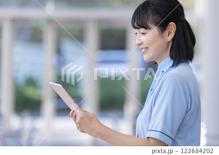施設スタッフ イメージ タブレットを持ったミドル女性の横顔 施設スタッフ イメージ タブレットを持ったミドル女性の横顔 122684202