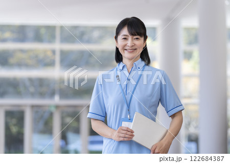 カメラ目線で笑顔のタブレットを持った女性施設スタッフ カメラ目線で笑顔のタブレットを持った女性施設スタッフ 122684387