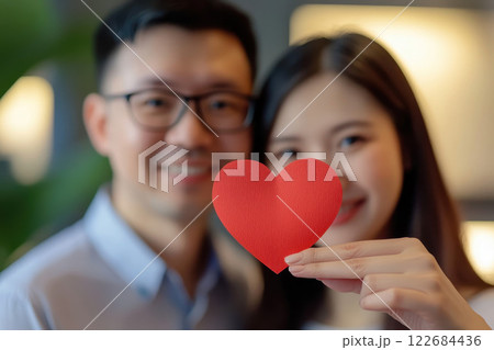 love, valentines day and relationships concept - happy Asian couple holding red heart together at home. 122684436