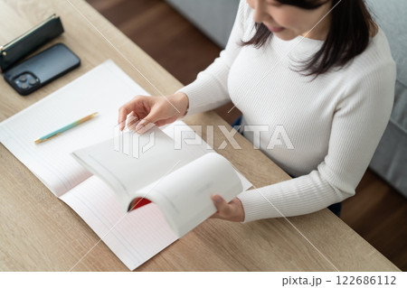 リスキリングのため参考書を確認する女性　顔無し 122686112