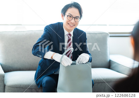 中古品査定のため家を訪問して見積もり確認をする買取業者と主婦 122686128