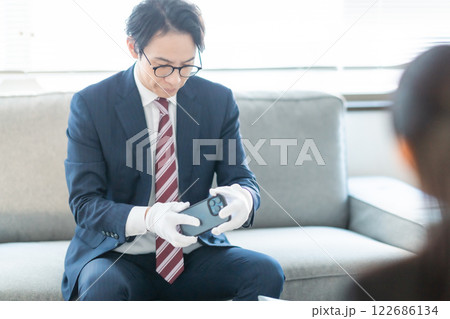 中古品査定のため家を訪問して見積もり確認をする買取業者と主婦 122686134