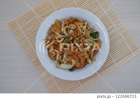 plate of stir-fried noodles with vegetables, bean sprouts, and chili slices, served on a bamboo mat plate of stir-fried noodles with vegetables, bean sprouts, and chili slices, served on a bamboo mat 122686723