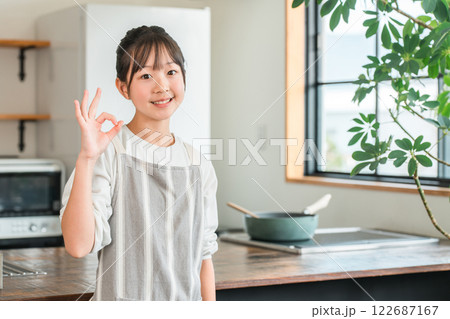 家のキッチンにいるエプロン姿の小学生・中学生の女の子 122687167
