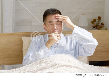 咳をするパジャマを着た中年の男性 122687276
