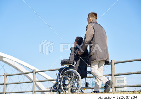 妻が乗る車椅子を押して散歩する夫 妻が乗る車椅子を押して散歩する夫 122687284