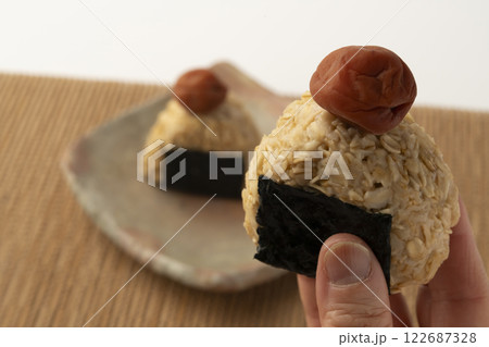 オートミールごはんのおにぎりを手で持ち上げる 122687328