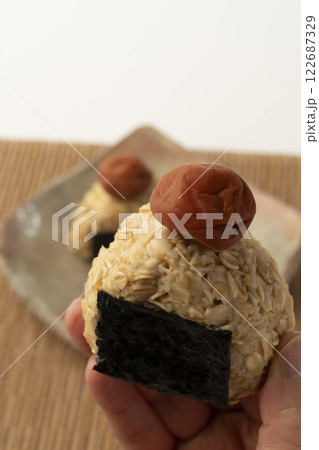 オートミールごはんのおにぎりを手で持ち上げる 122687329