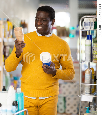 Man selects and purchases paper cups in the household goods section of supermarket Man selects and purchases paper cups in the household goods section of supermarket 122687434