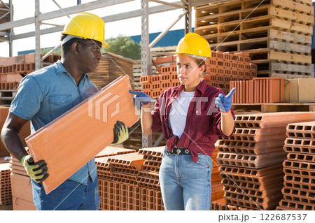 Female manager pointing to worker where to carry bricks 122687537
