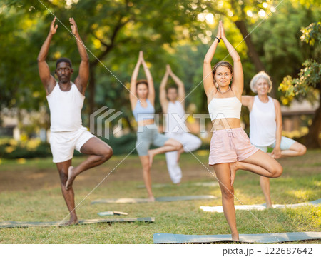 Group of multinational people practitioner performing Garudasana in garden 122687642