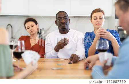 African American man playing poker with friends at kitchen table African American man playing poker with friends at kitchen table 122687750