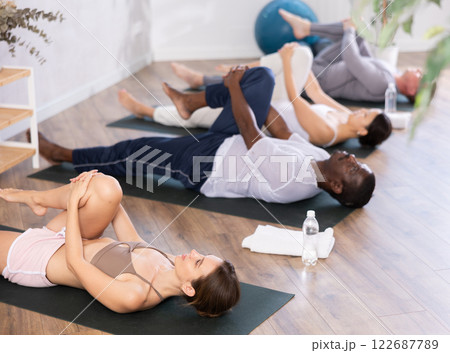 Young woman doing stretching Ardha Pawanmuktasana in yoga studio 122687789