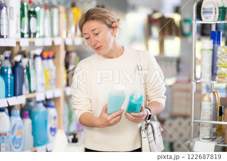 Female buyer chooses shampoo or shower gel in household goods department of supermarket 122687819