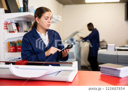 Technical worker of printing house calculates cost of payment for work on calculator 122687854