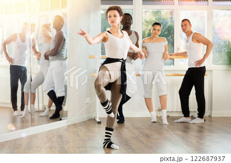 Female ballet instructor demonstrating movements to group of dancers 122687937