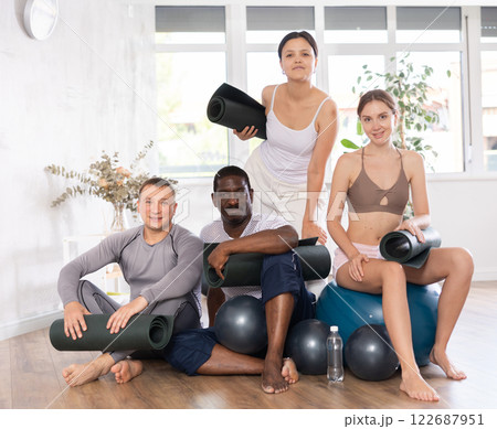 Group of smiling sporty females and males of different ages in sportswear with fitness balls and mats posing together in sports Group of smiling sporty females and males of different ages in sportswear with fitness balls and mats posing together in sports 122687951