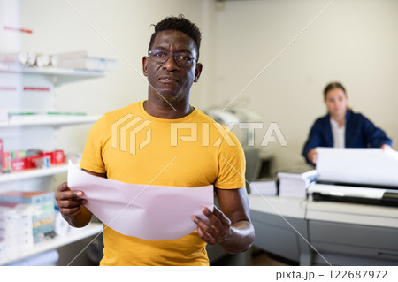 Focused African American man checking the print quality and accepting color proofs in the printer house Focused African American man checking the print quality and accepting color proofs in the printer house 122687972