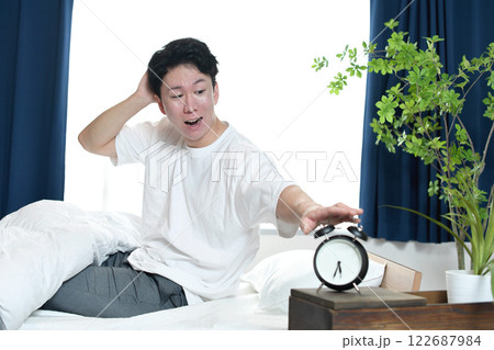 慌ててベッドから起きるアジア人の若い男性 慌ててベッドから起きるアジア人の若い男性 122687984
