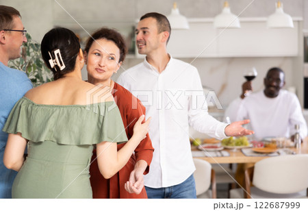 Smiling woman hostess hugging and kissing guest at dinner party Smiling woman hostess hugging and kissing guest at dinner party 122687999