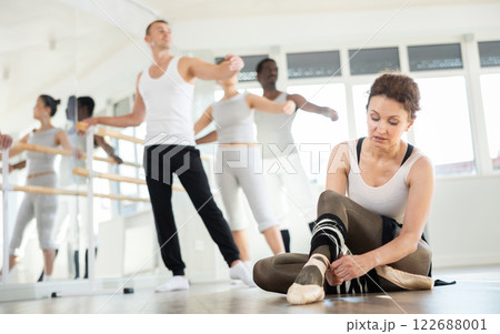 Woman dancer tying ribbons on pointe shoes Woman dancer tying ribbons on pointe shoes 122688001
