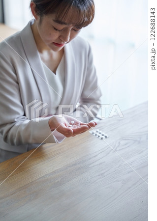 体調不良で薬を飲む女性 122688143