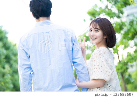 振り向いてピースをする女性 男女カップルイメージ 振り向いてピースをする女性 男女カップルイメージ 122688697