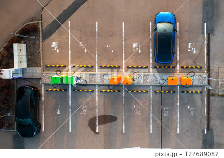 Top view of a blue electric car powers up at an EV charging station in the parking area. 122689087