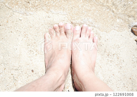 Woman's and men's feet on the sand at the beach in the summer. 122691008