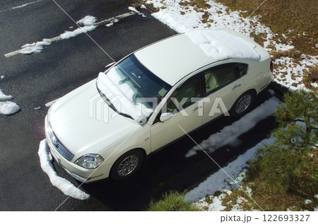 乗用車の窓に積もった雪が晴天の気温上昇で徐々に滑り落ちながら渦巻き状に丸まった珍しい自然現象 122693327