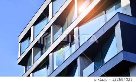 Modern apartment buildings on a sunny day with a blue sky. Facade of a modern apartment building. Glass surface with sunlight. 122694025