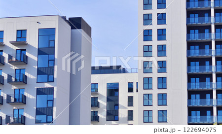 Modern apartment buildings on a sunny day with a blue sky. Facade of a modern apartment building. Glass surface with sunlight. Modern apartment buildings on a sunny day with a blue sky. Facade of a modern apartment building. Glass surface with sunlight. 122694075