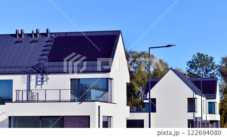 Terraced family homes in newly developed housing estate. The real estate market in the suburbs. New single family houses in a new development area. Residential homes with modern facade.  122694080