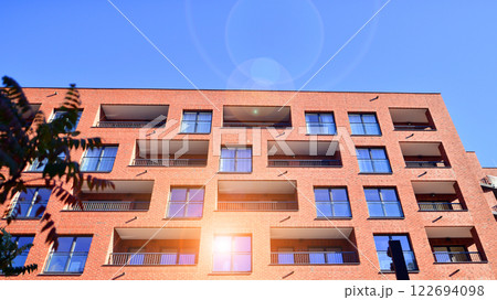 Modern apartment buildings on a sunny day with a blue sky. Facade of a modern apartment building. Glass surface with sunlight. Modern apartment buildings on a sunny day with a blue sky. Facade of a modern apartment building. Glass surface with sunlight. 122694098