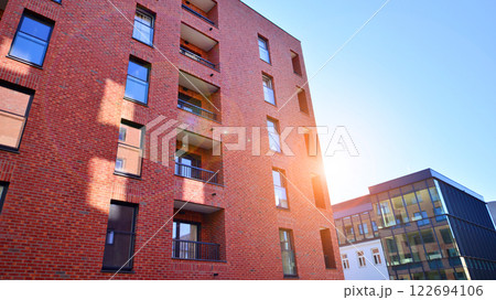 Modern apartment buildings on a sunny day with a blue sky. Facade of a modern apartment building. Glass surface with sunlight. Modern apartment buildings on a sunny day with a blue sky. Facade of a modern apartment building. Glass surface with sunlight. 122694106