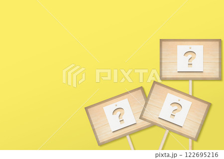 はてなが切り抜かれた紙が貼られたひのきの看板が右側に掲げられた黄色い背景 はてなが切り抜かれた紙が貼られたひのきの看板が右側に掲げられた黄色い背景 122695216