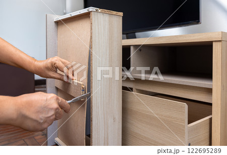 Handyman fixing over tight drawer slides of TV shelf. Concept Fix stuck wooden drawer slides Handyman fixing over tight drawer slides of TV shelf. Concept Fix stuck wooden drawer slides 122695289