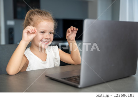 Little girl does finger gymnastics online on the laptop home. Distance learning concept. 122696193