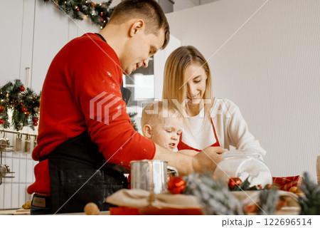 Side view of happy funny family mother, father and little son bake christmas cookies on cozy kitchen at home Side view of happy funny family mother, father and little son bake christmas cookies on cozy kitchen at home 122696514