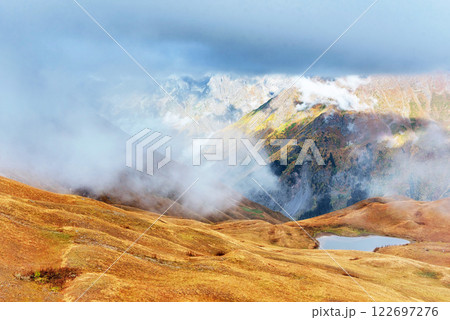 Majestic mountain landscape. Koruldi lakes and a tourist admiring the view. Active life concept Majestic mountain landscape. Koruldi lakes and a tourist admiring the view. Active life concept 122697276