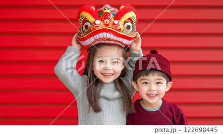 Asian children celebrating with lion dance costume against vibrant red background 122698445