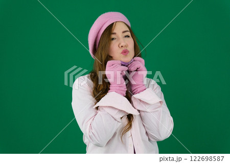Young stylish woman wearing pink warm coat, pants and handbag walking in the city street in cold season. Winter fashion, elegant look, outfit in pastel colors. Plus size model. 122698587