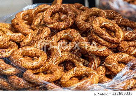 A large pile of golden-brown simits, traditional Turkish bagels, fills a clear plastic bag. The sesame-seeded rings are freshly baked, appealing and delicious-looking A large pile of golden-brown simits, traditional Turkish bagels, fills a clear plastic bag. The sesame-seeded rings are freshly baked, appealing and delicious-looking 122699333