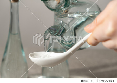 White distilled vinegar is poured into spoon 122699434