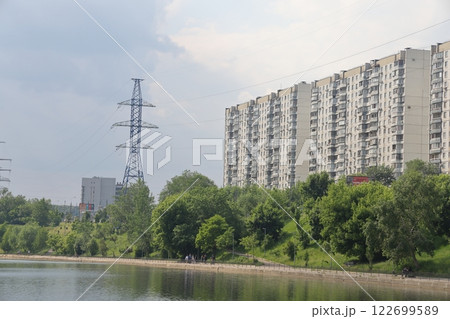Lush greenery of trees and lawns around the pond in the park, urban landscape park. 122699589
