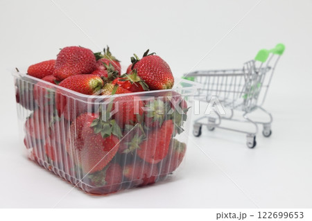 Plastic basket of strawberries on the background of a grocery cart, rising food prices, food crisis. Plastic basket of strawberries on the background of a grocery cart, rising food prices, food crisis. 122699653