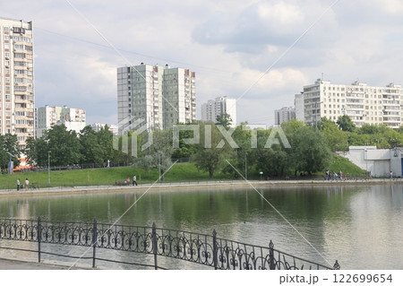 Lush greenery of trees and lawns around the pond in the park, urban landscape park. Lush greenery of trees and lawns around the pond in the park, urban landscape park. 122699654
