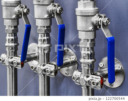 Valves and fittings installed on a wall in a mechanical workshop demonstrating industrial infrastructure 122700544