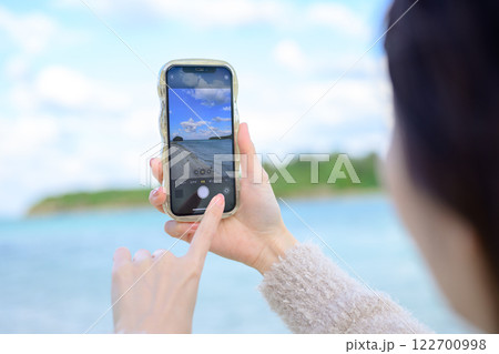 海を眺めながら写真を撮る女性 海を眺めながら写真を撮る女性 122700998