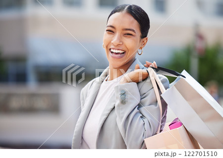 Shopping, retail and sale with a young woman in the city to spend money and shop at a store or mall. Portrait of a happy, carefree and urban customer with a smile holding bags out on the town 122701510